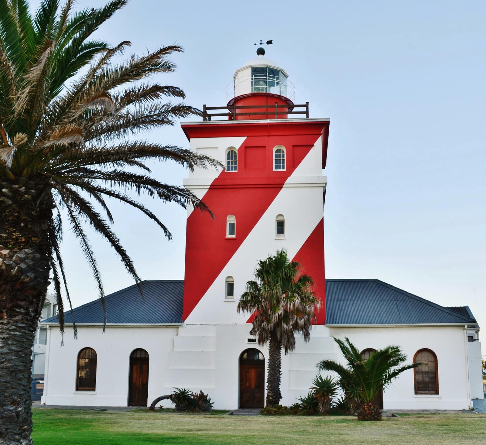 Der rot-weiß gestreifte Leuchtturm von Green Point hinter Palmen